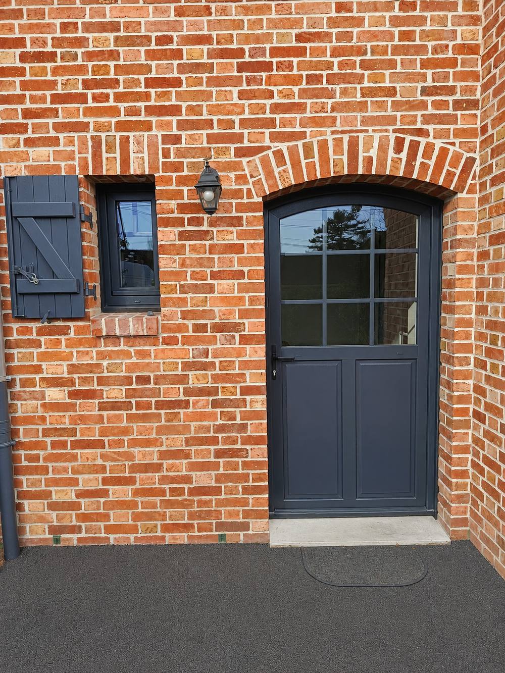 Porte d'entrée et fenêtre en aluminium gris anthracite, encadrement brique, réalisation F I R Menuiserie