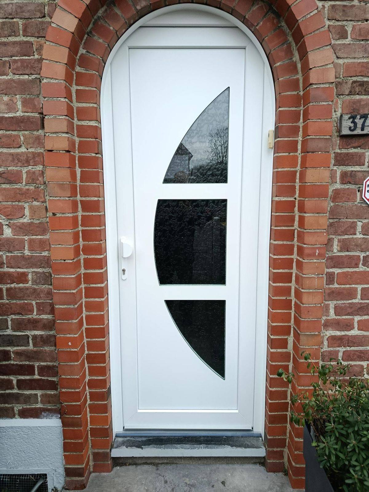 Porte d'entrée PVC blanche sur mesure, baie cintrée en encadrement brique